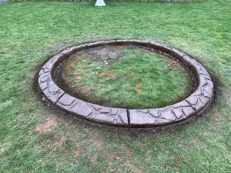 a fire pit is sitting in the middle of a lush green lawn