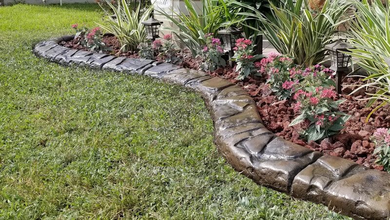 a lawn with a concrete curb and flowers in the middle of it