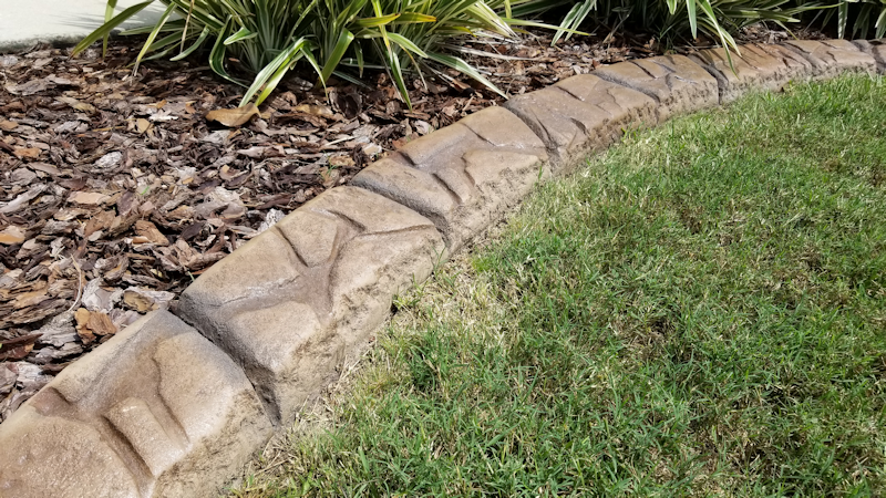 a stone edging is sitting on top of a lush green lawn
