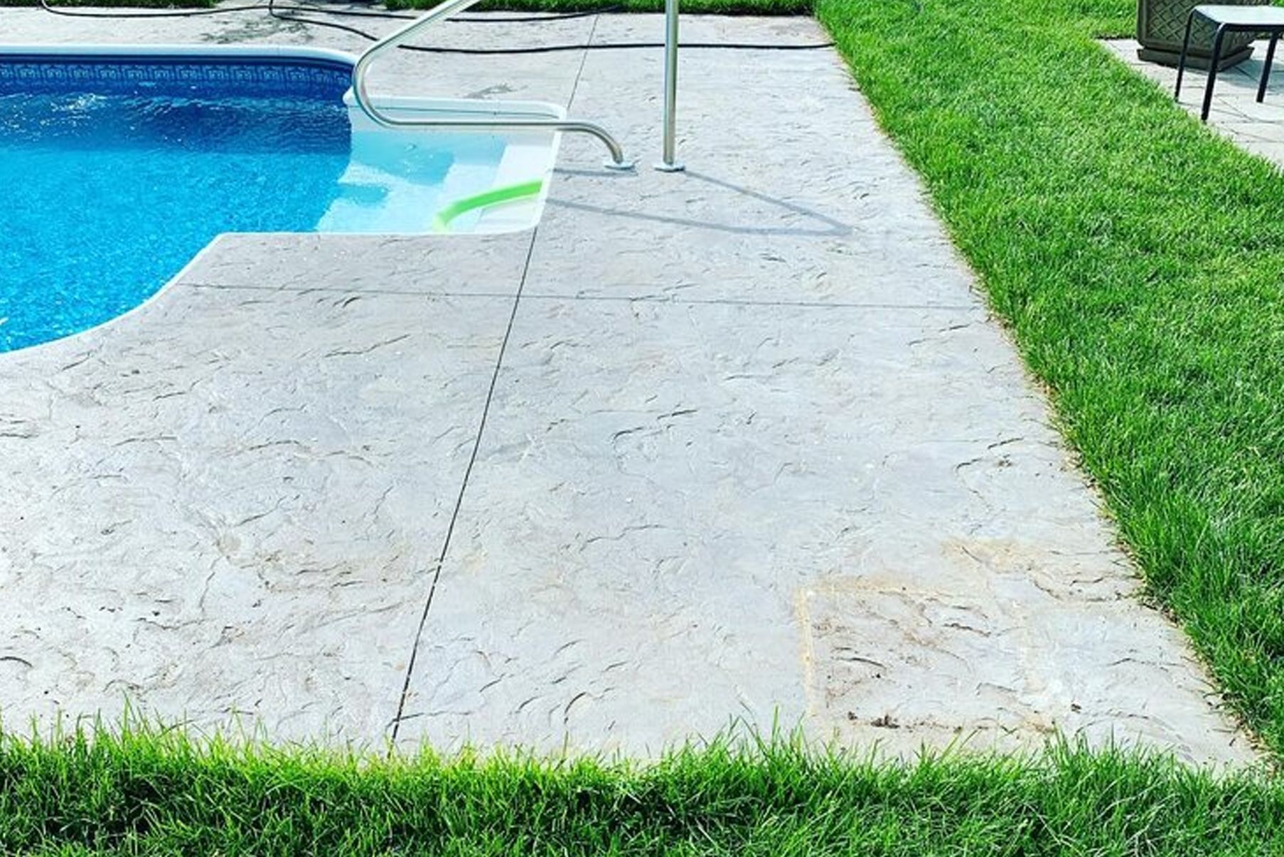 a swimming pool is surrounded by a lush green lawn .