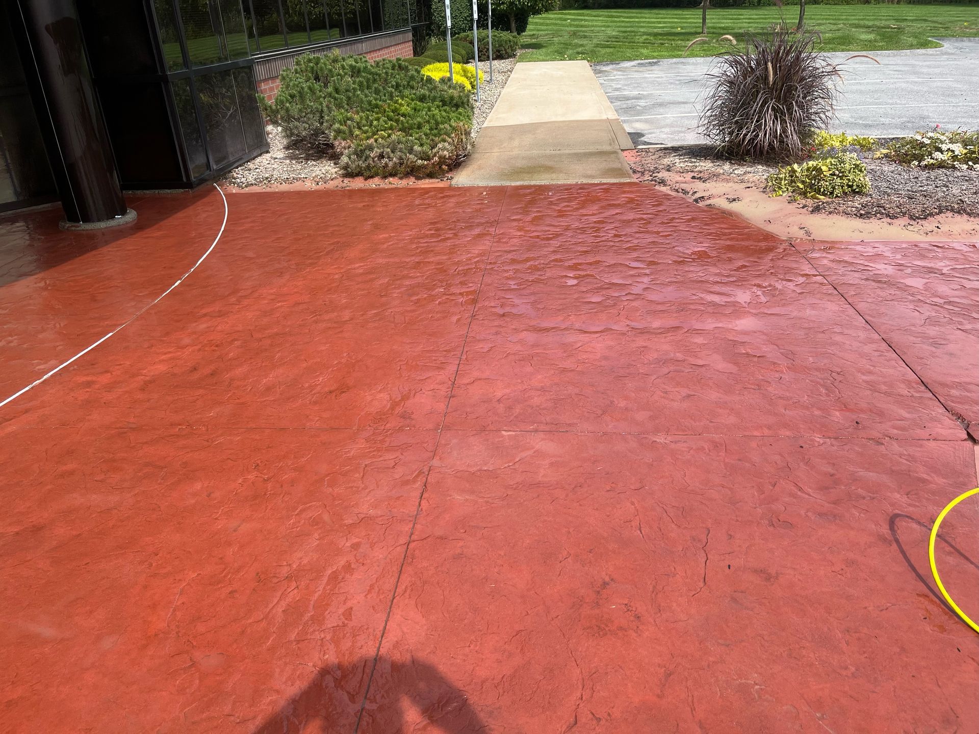 a red concrete driveway with a yellow hose attached to it