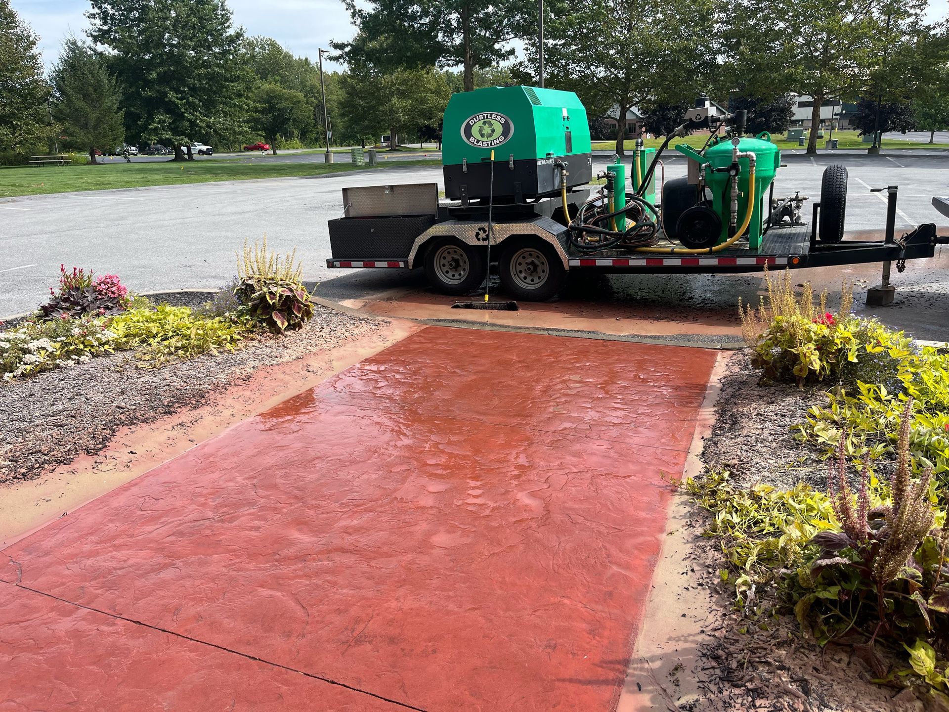a green machine is parked on a trailer in a parking lot