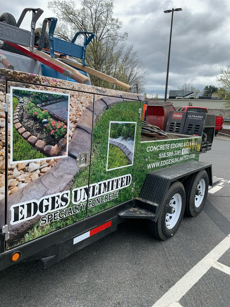 a trailer with a wrap on it is parked in a parking lot .