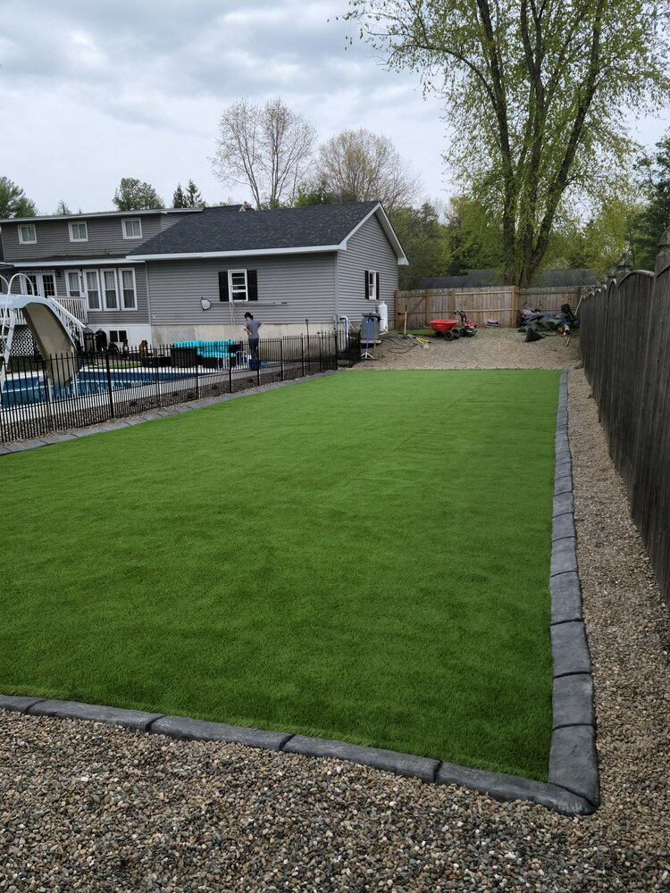 a backyard with a large lawn and a house in the background .