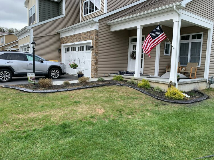 a car is parked in front of a house with an american flag on the porch .