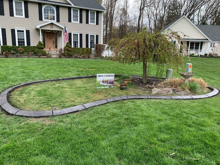 there is a concrete curb in the middle of the grass in front of a house .