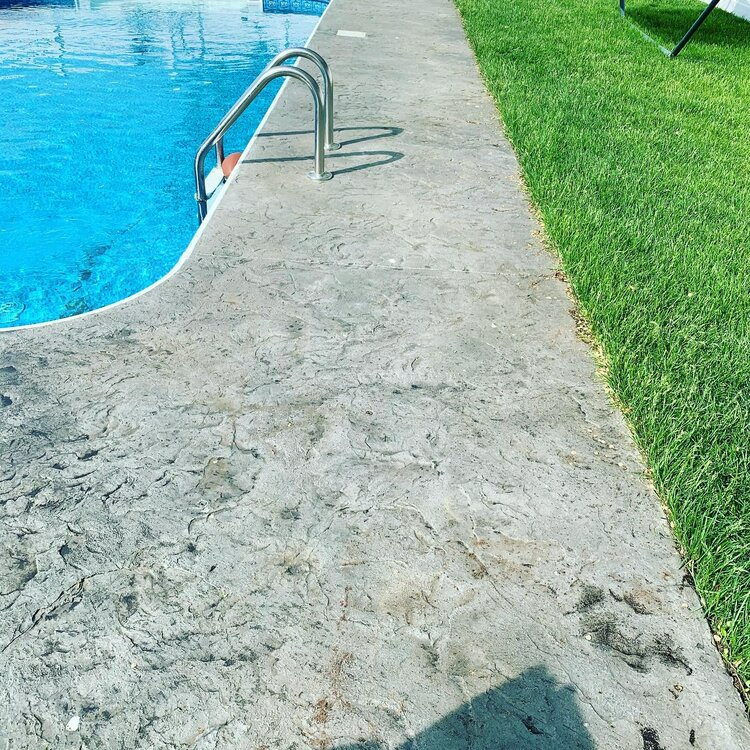 a concrete walkway leading to a swimming pool .