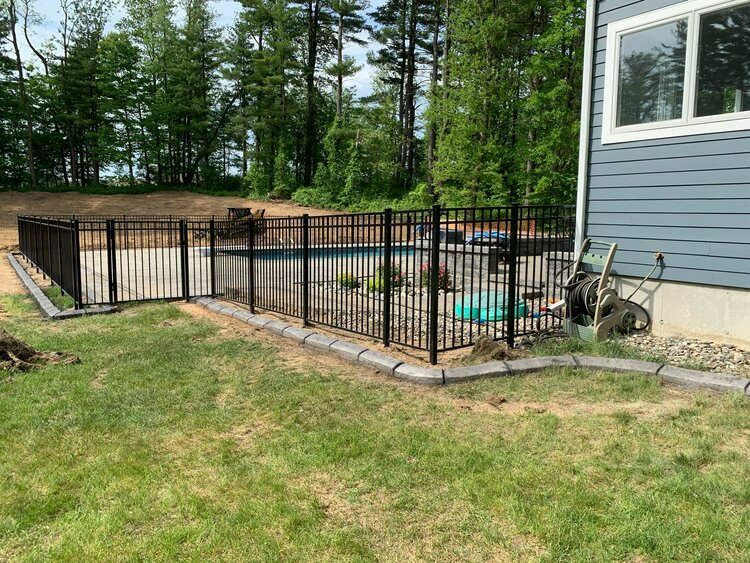 a black fence surrounds a swimming pool in a backyard .