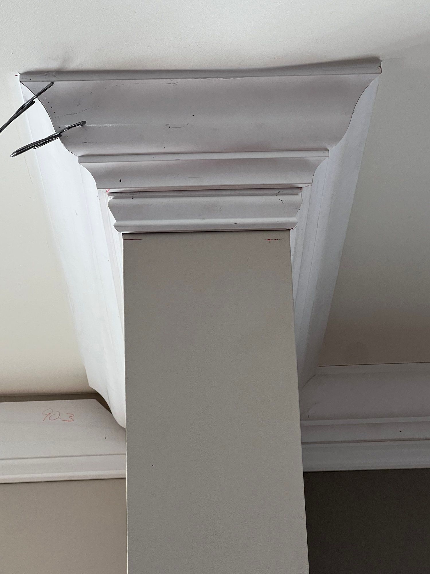a white molding on the ceiling of a room next to a column