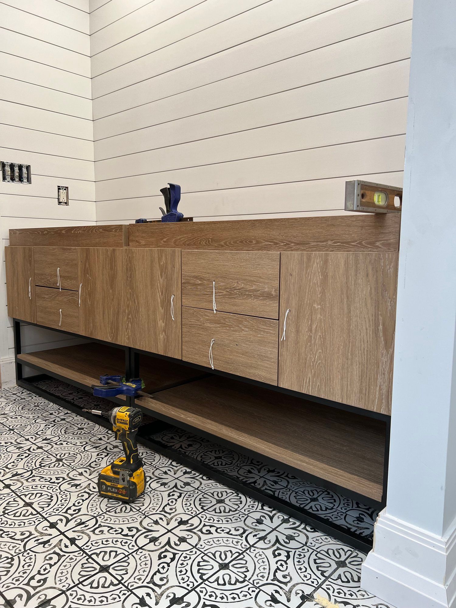 a bathroom with a wooden vanity and a drill on the floor