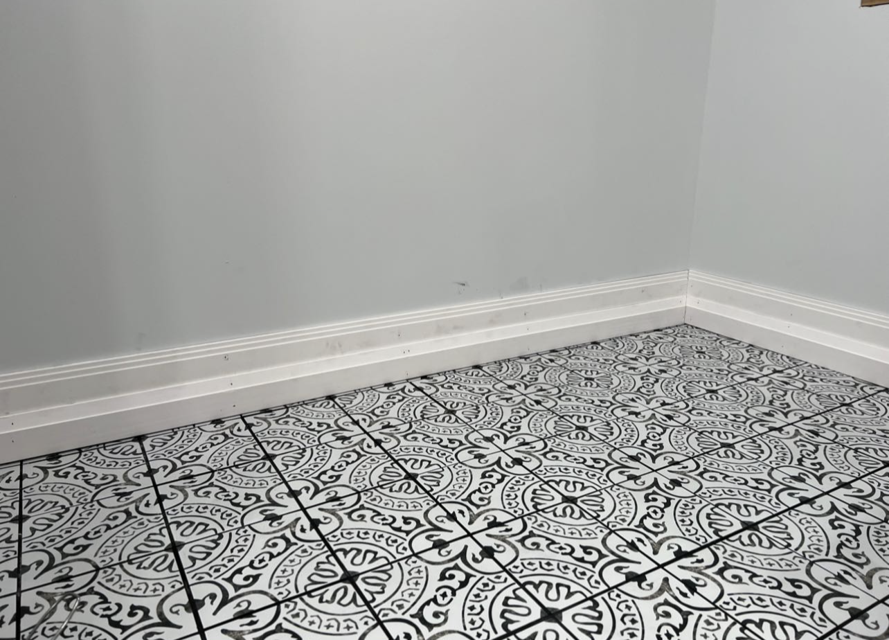 a corner of a room with a black and white tile floor