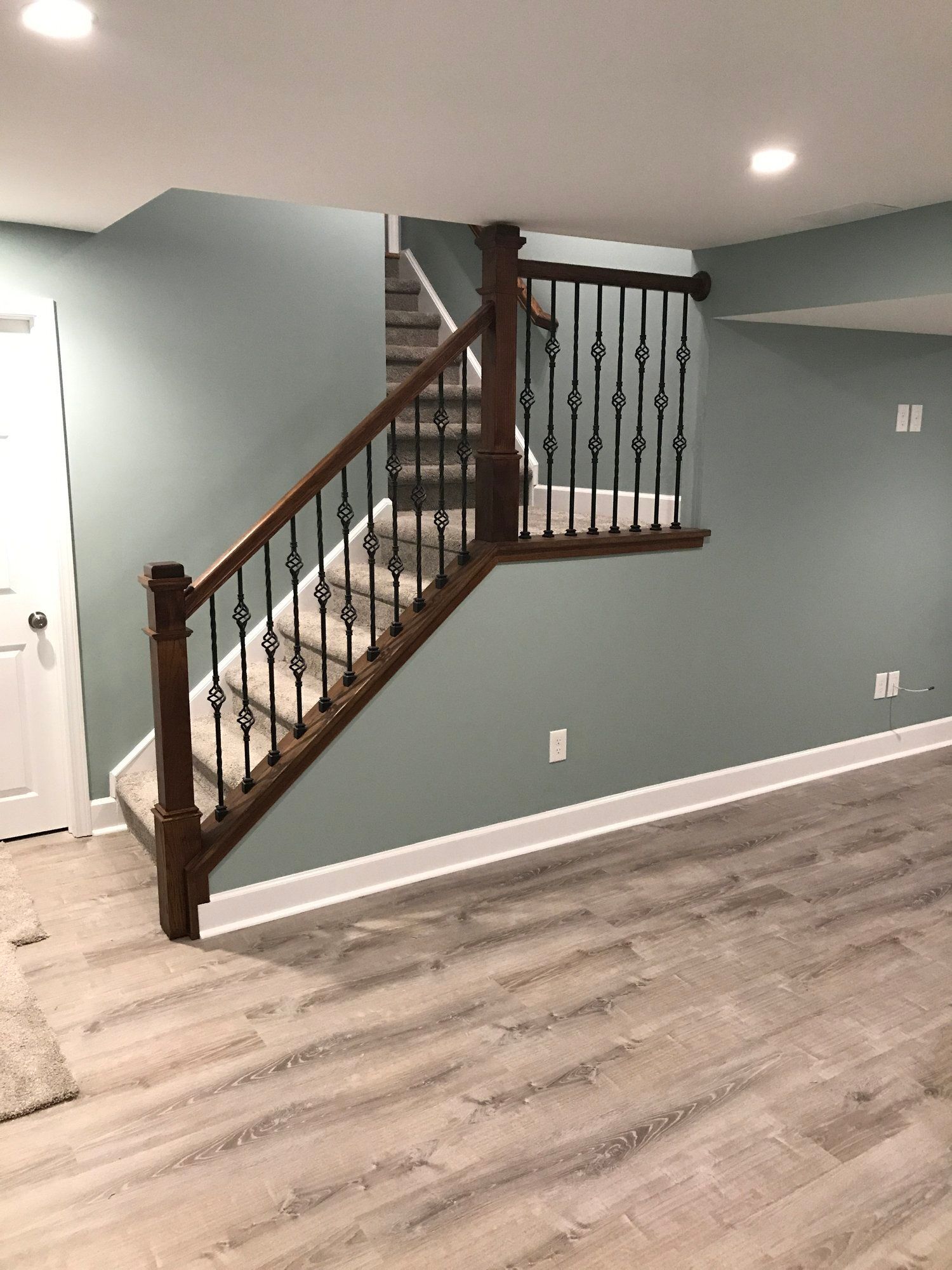 a basement with stairs and a wrought iron railing