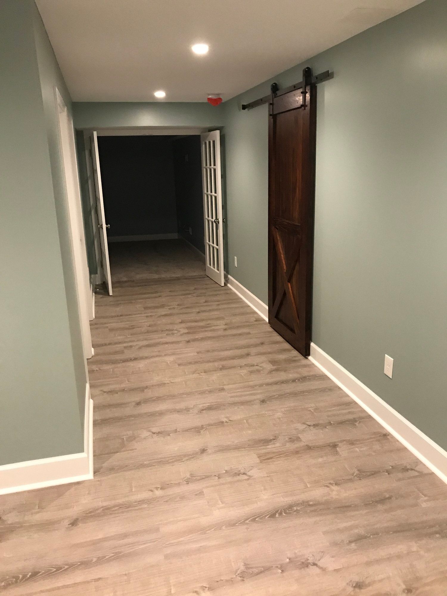 a hallway in a basement with a sliding barn door