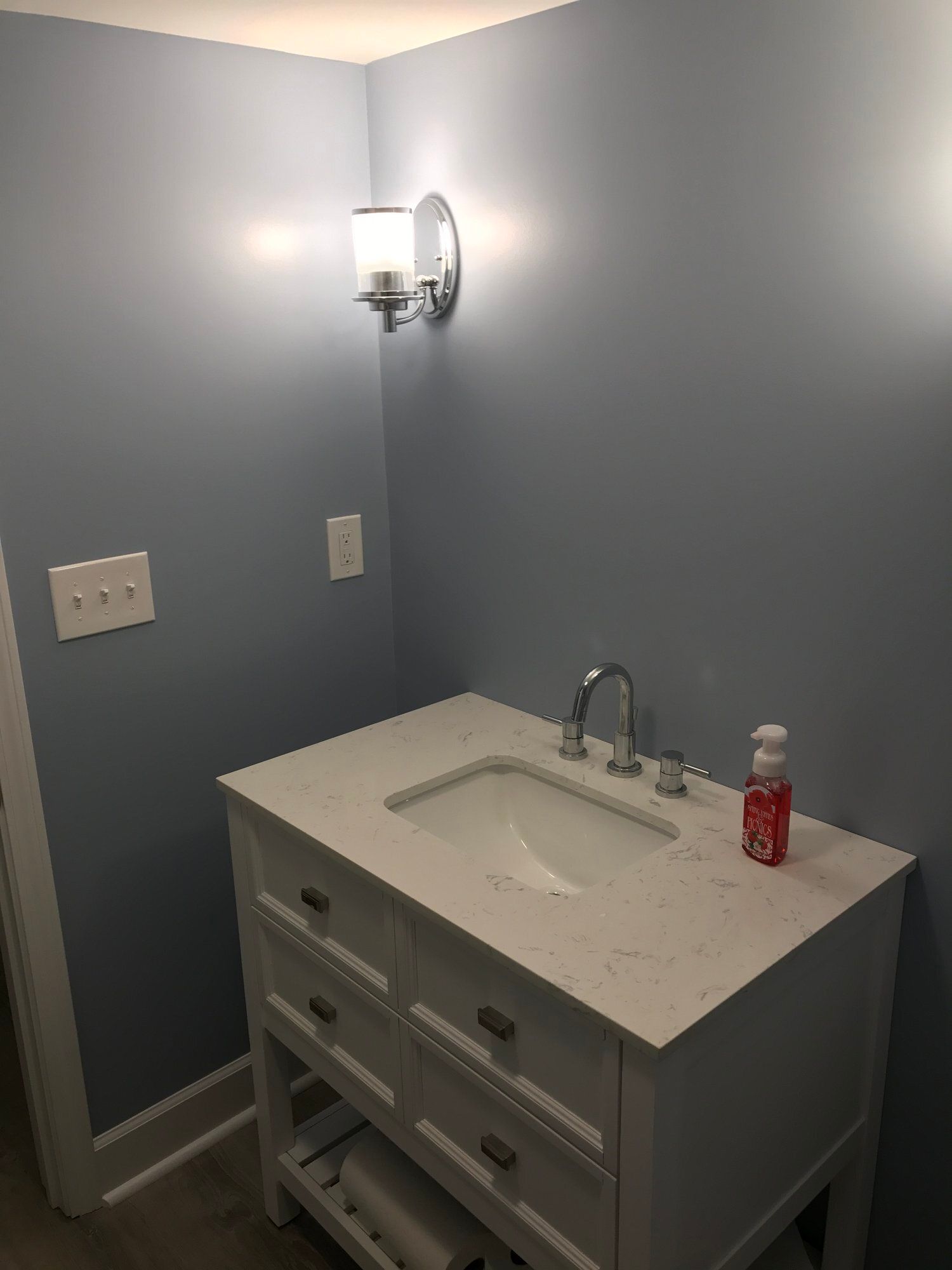 a bathroom with a sink and a light on the wall
