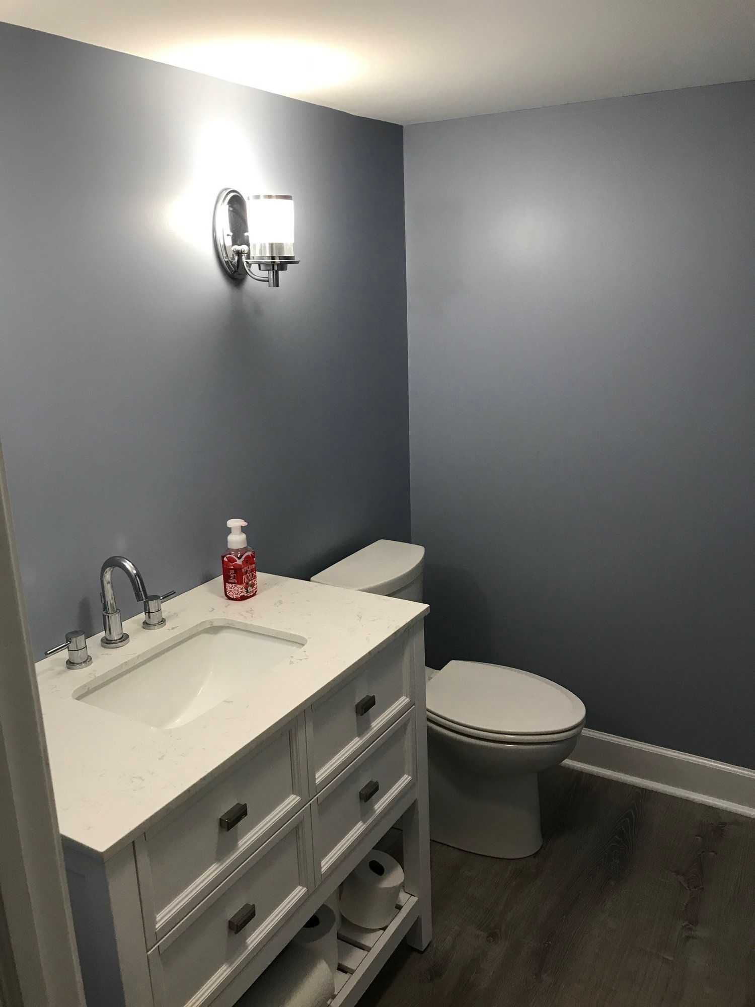 a bathroom with a sink, toilet and light on the wall