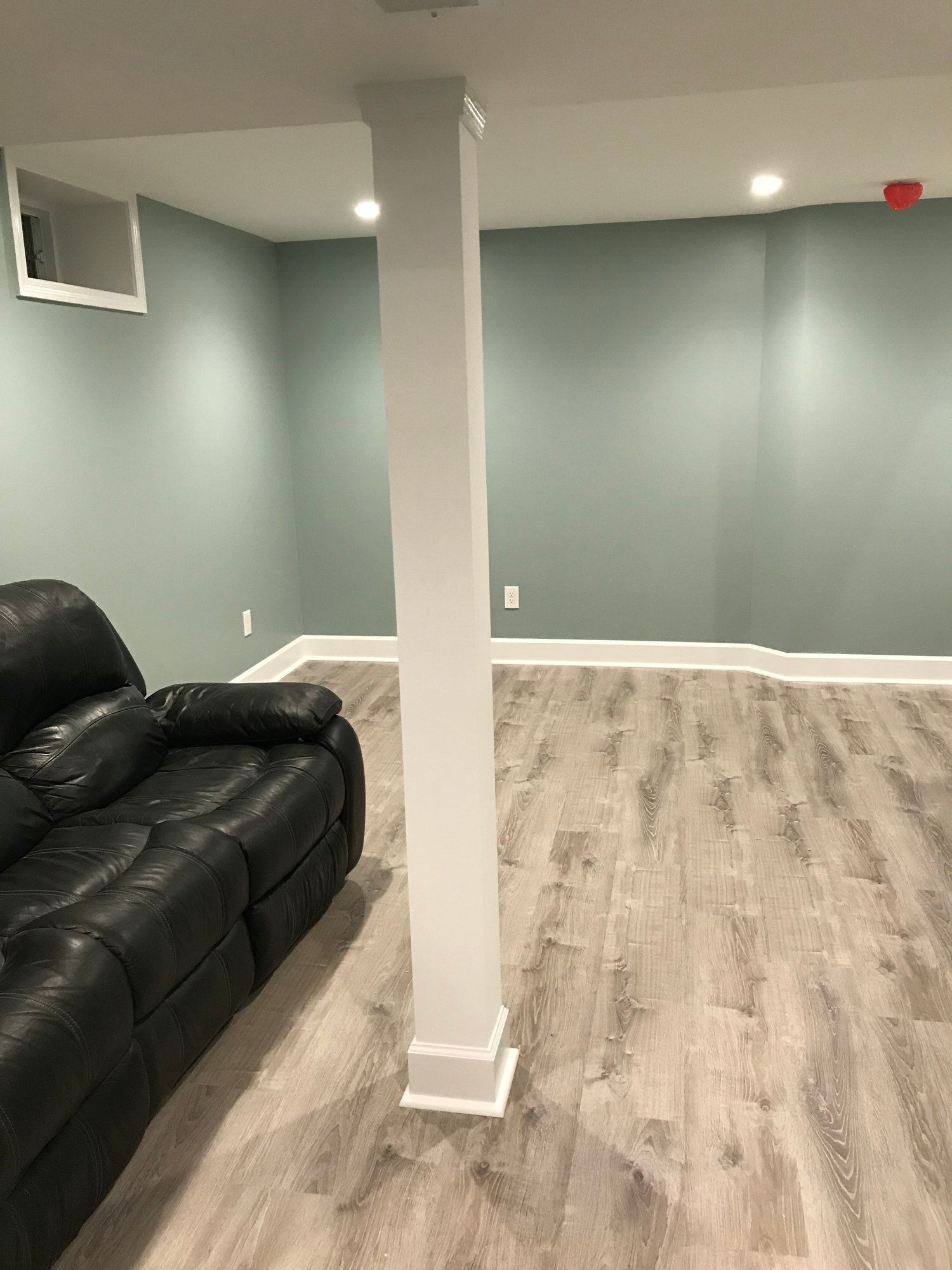 a living room in a basement with a couch and a white column