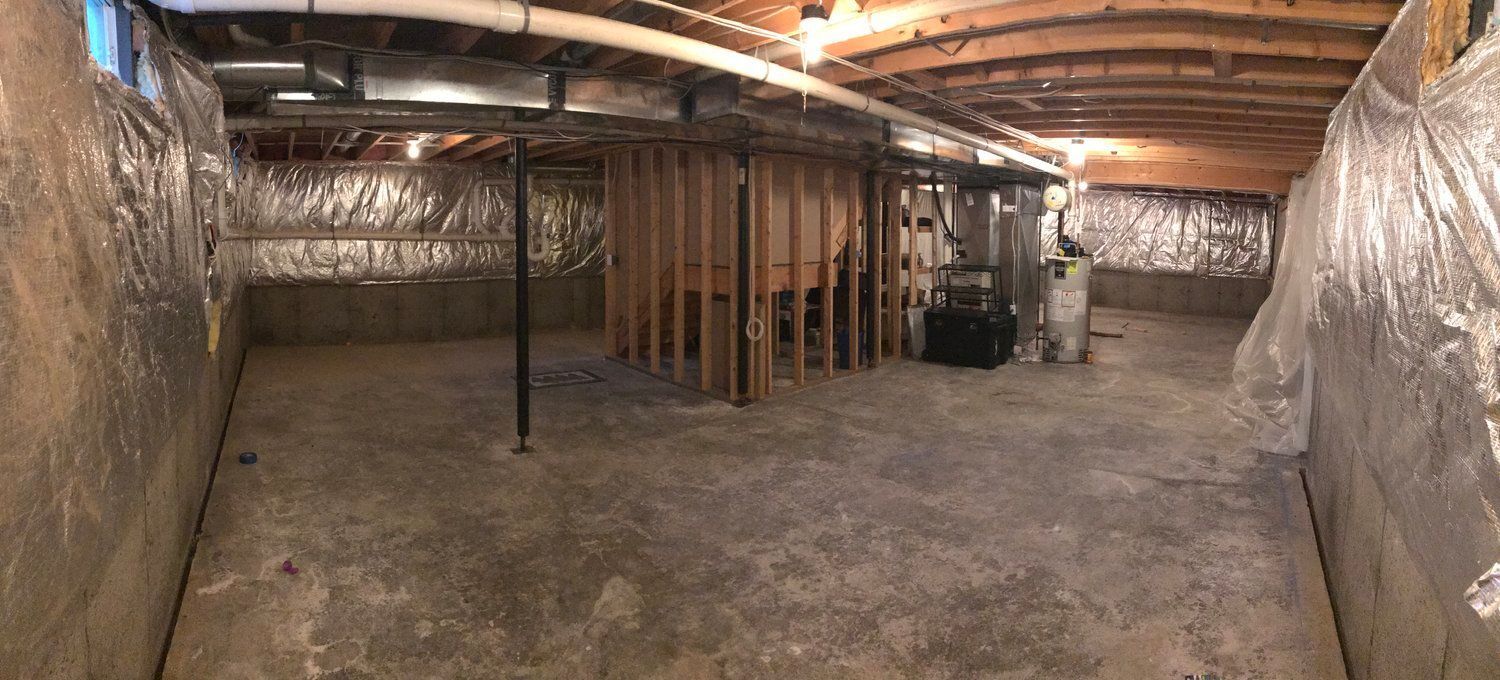 a large empty basement with a lot of pipes hanging from the ceiling