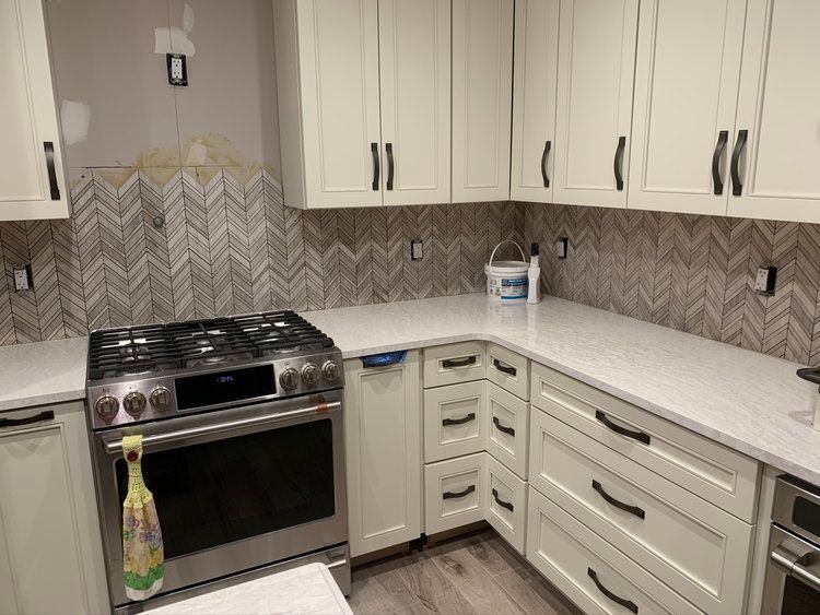 a kitchen with white cabinets, stainless steel appliances, and a stove
