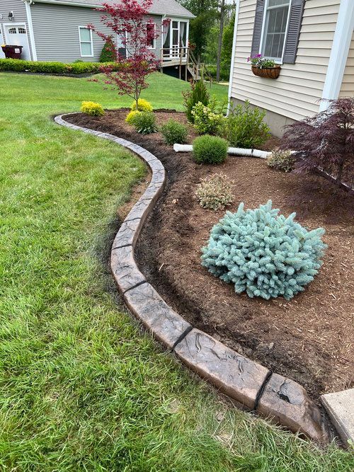 a lawn with a concrete curb and a house in the background