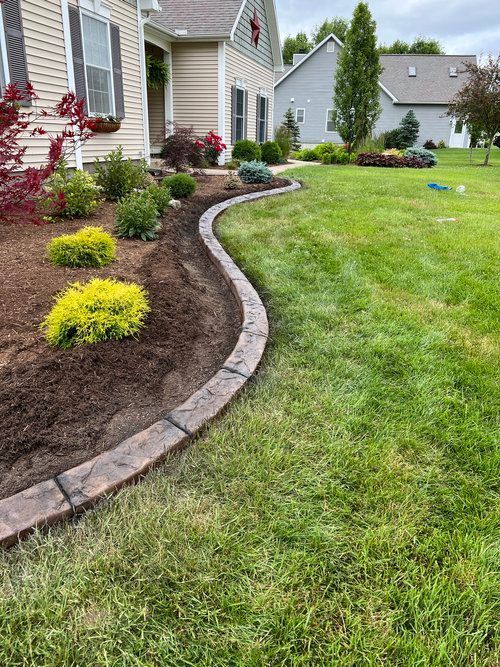 a lawn with a concrete curb and a house in the background
