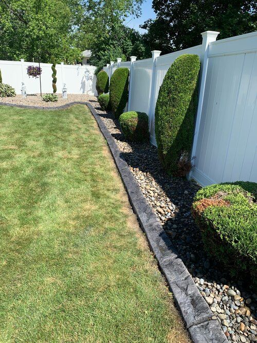 a white fence surrounds a lush green lawn