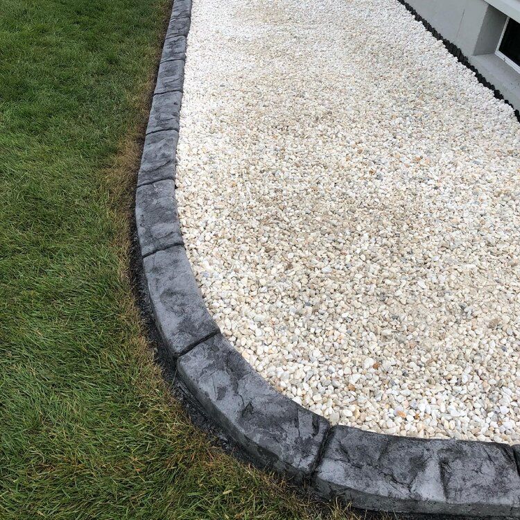 a sidewalk with gravel and grass on the side of it