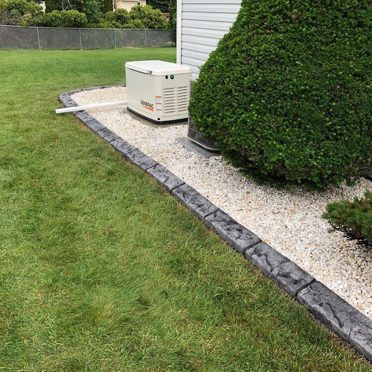 a generator is sitting in the grass next to a concrete curb