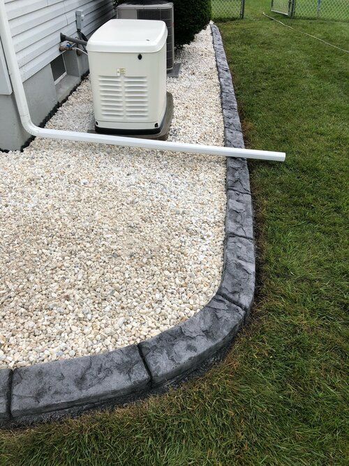 a generator is sitting on top of a gravel patio next to a house