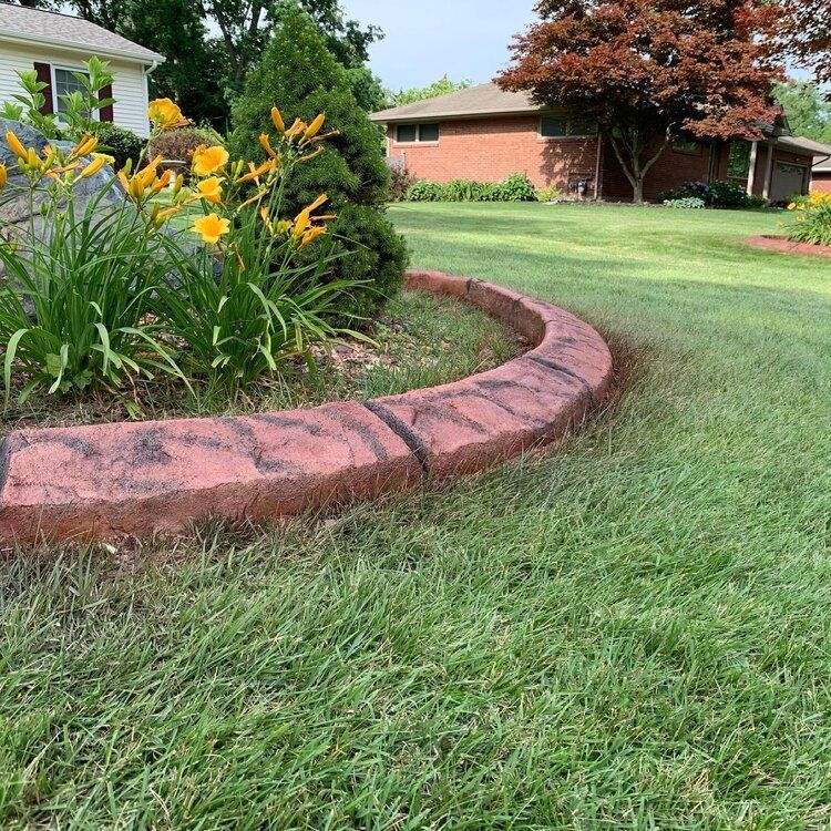 there is a brick curb in the middle of a lush green lawn