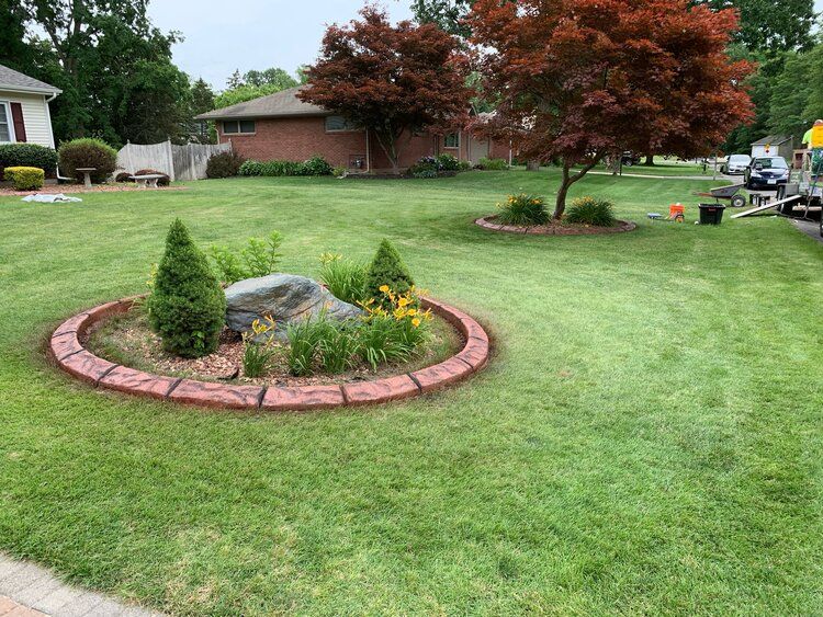 a lush green lawn with a brick border and a tree in the middle