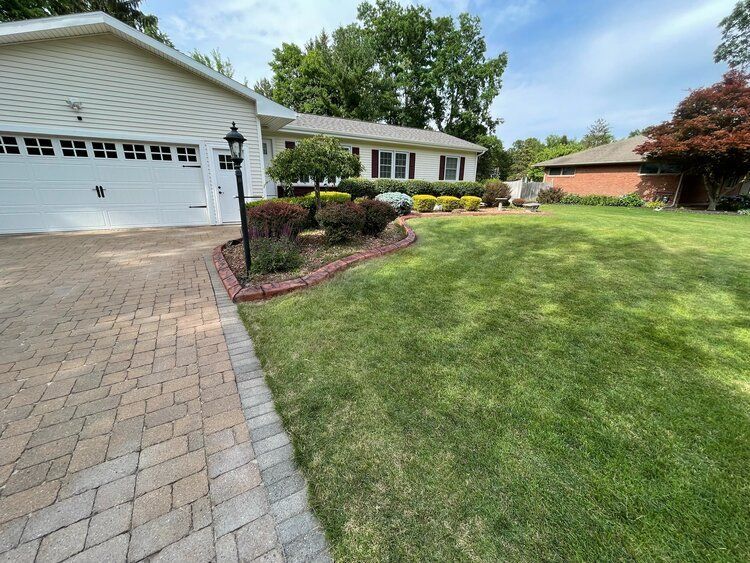 a house with a brick driveway and a large lawn in front of it