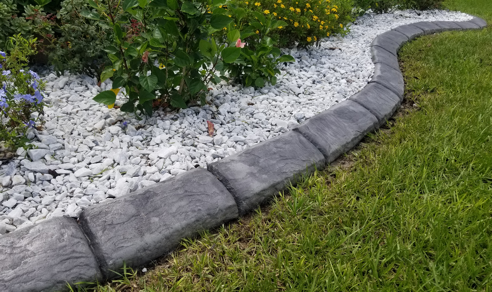 a garden with a stone edging and white gravel