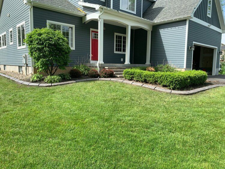 a blue house with a red door and a lush green lawn in front of it