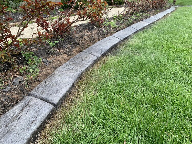 a concrete curb in the middle of a lush green lawn