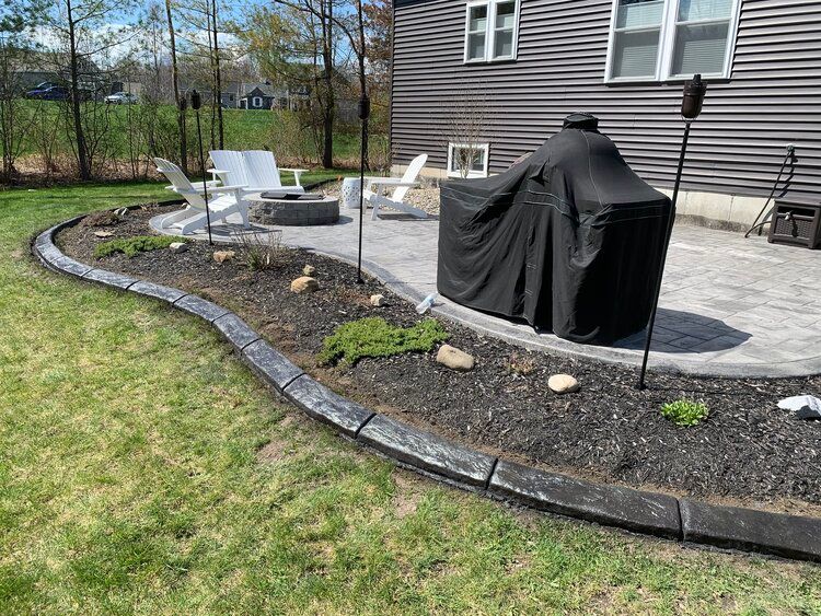 a patio with a grill and chairs in the backyard of a house