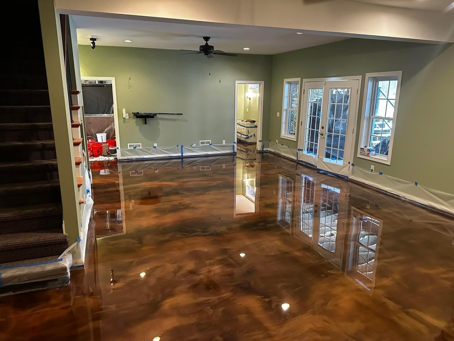 Metallic epoxy floor in a room with green walls and French doors, reflecting the space.