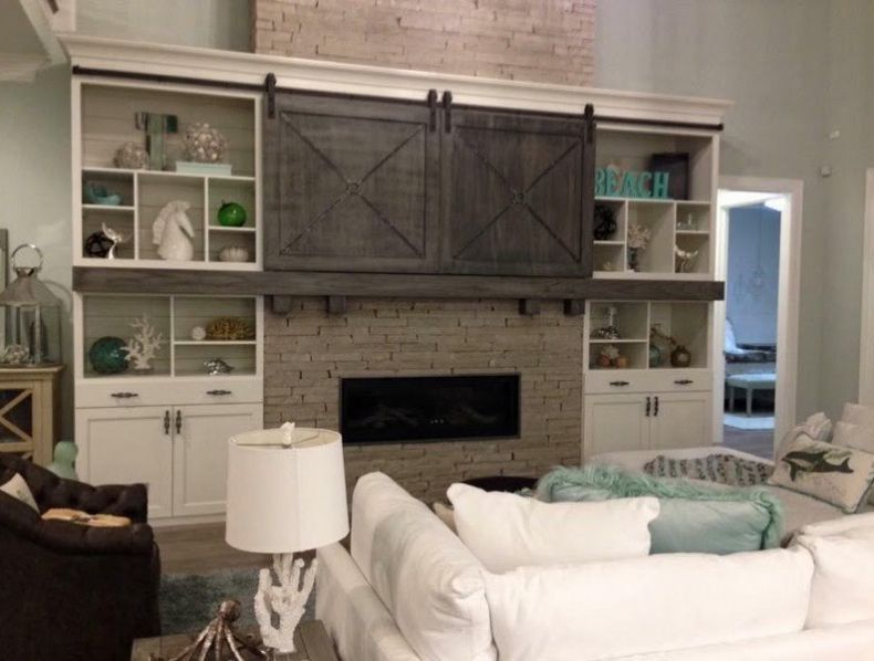 Fireplace with built-in shelves, sliding barn doors, and white cabinets. Coastal decor in a living room.