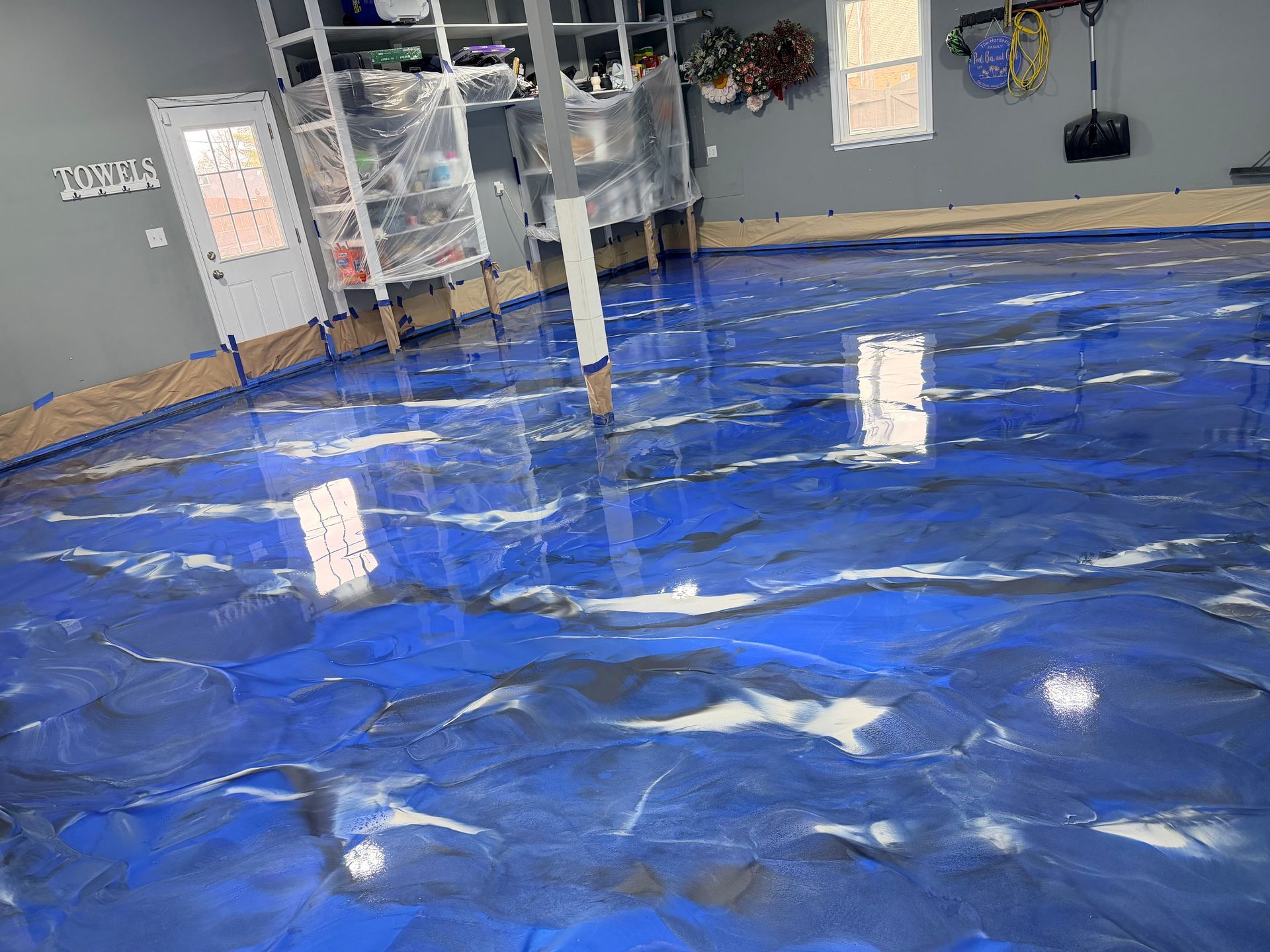 Blue and white epoxy garage floor with reflective sheen.