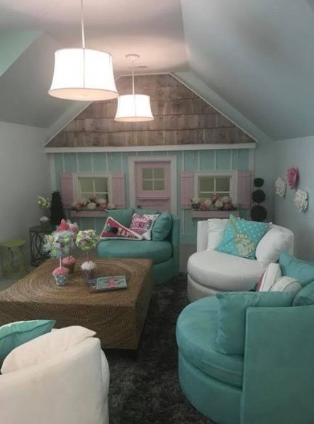 Cozy, pastel-colored playroom with custom playhouse wall, teal and white seating, and hanging lights.