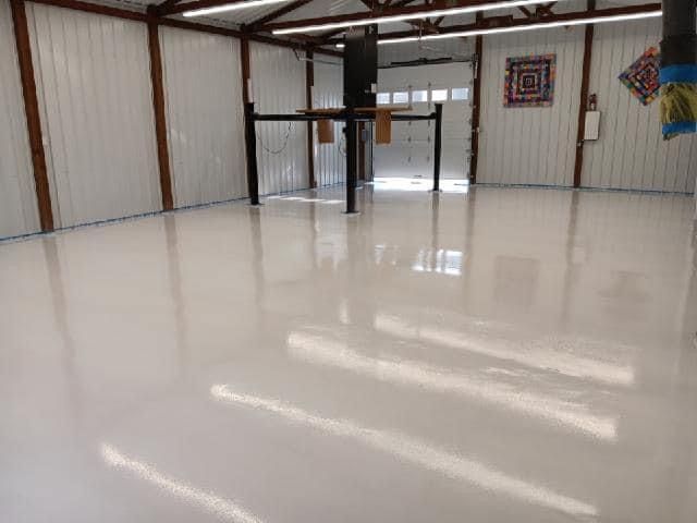 Spacious white-floored interior of a garage or workshop with a vehicle lift and targets visible.