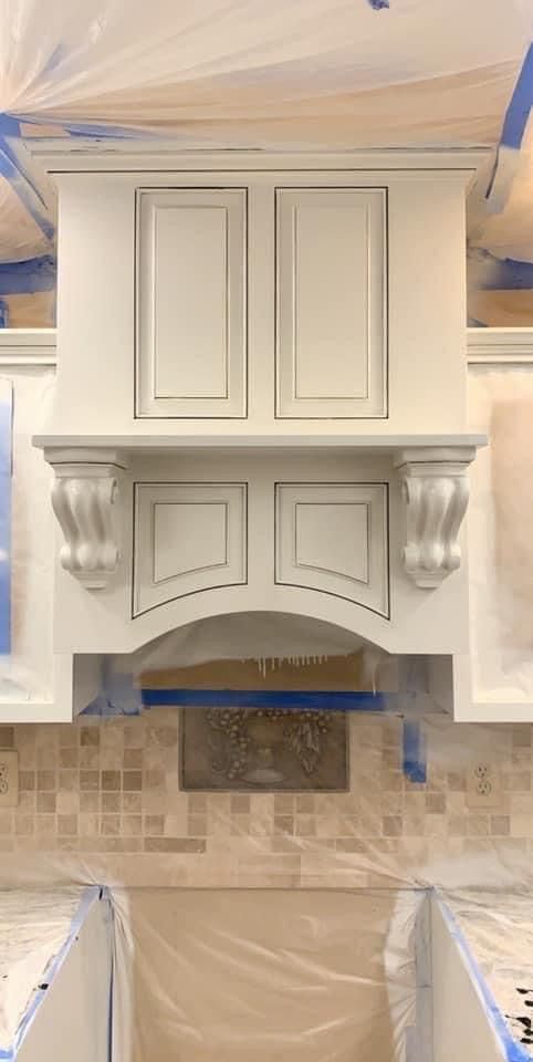 White painted kitchen range hood with corbels and mosaic tile backsplash.