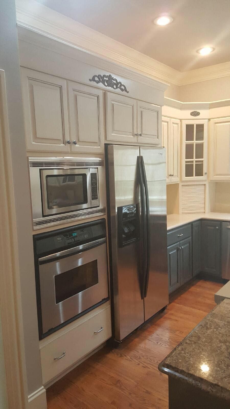 Kitchen with white and gray cabinets, stainless steel appliances, and wood flooring.