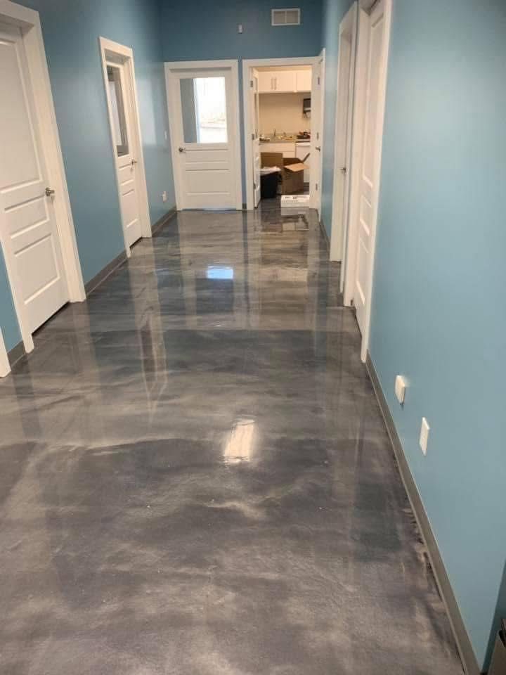 Hallway with glossy gray epoxy floor, blue walls, white doors, and a glimpse into another room.