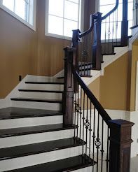 Staircase with white risers and dark wood treads and banister. Iron balusters and window in background.