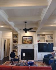 Living room with a fireplace, built-in shelves, TV, and black ceiling fan.