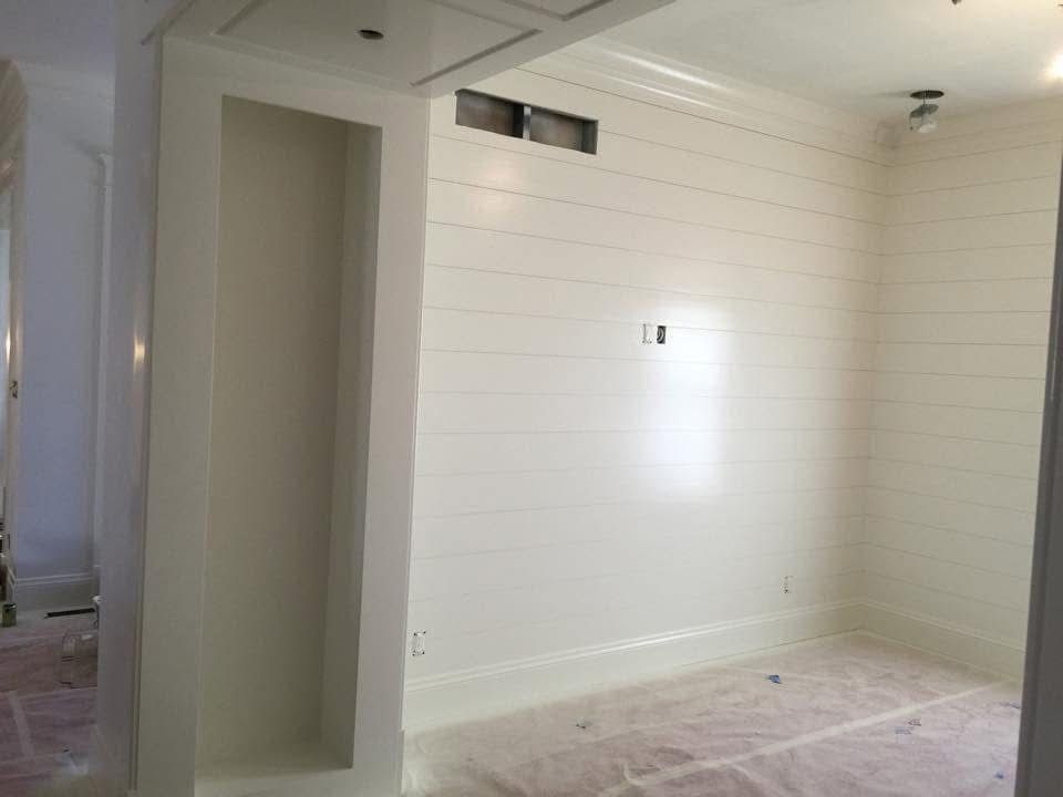 White paneled room with built-in shelves and horizontal shiplap walls.