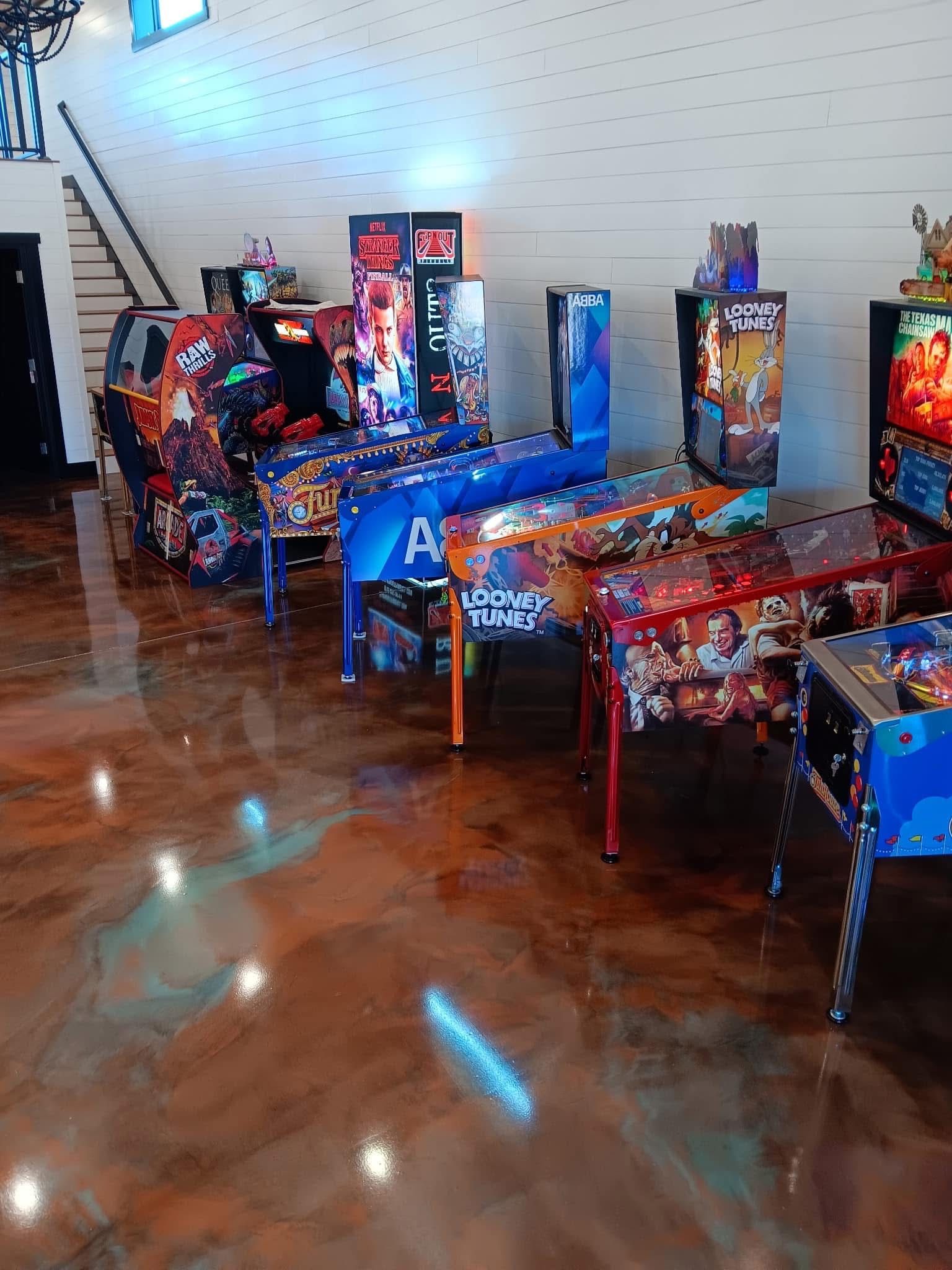 Pinball machines in a game room with reflective, glossy flooring.