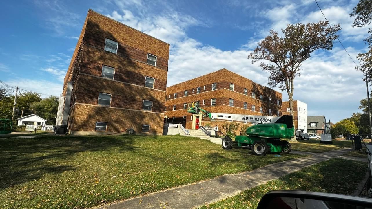 Brick apartment buildings with green lawn, blue sky, and a green machine.