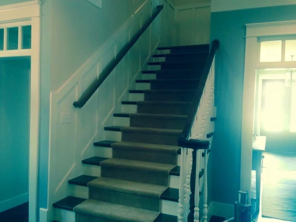 Staircase with carpeted steps and wooden handrails in a home.