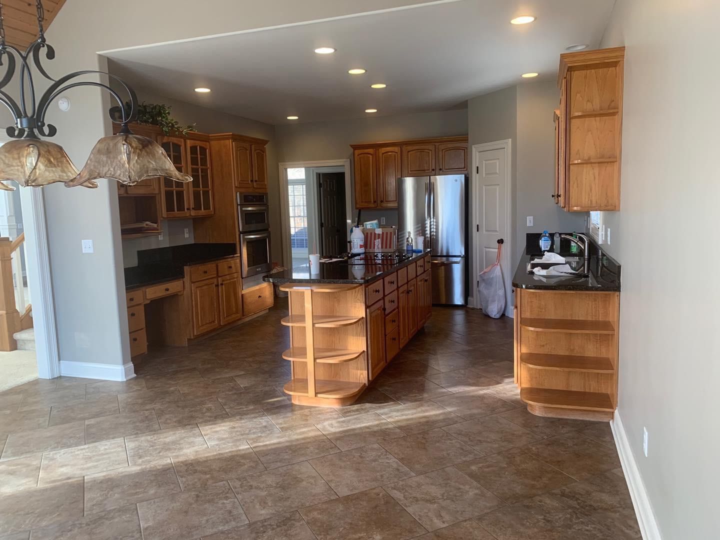 Spacious kitchen with wood cabinets, dark countertops, and large island with stainless steel appliances.